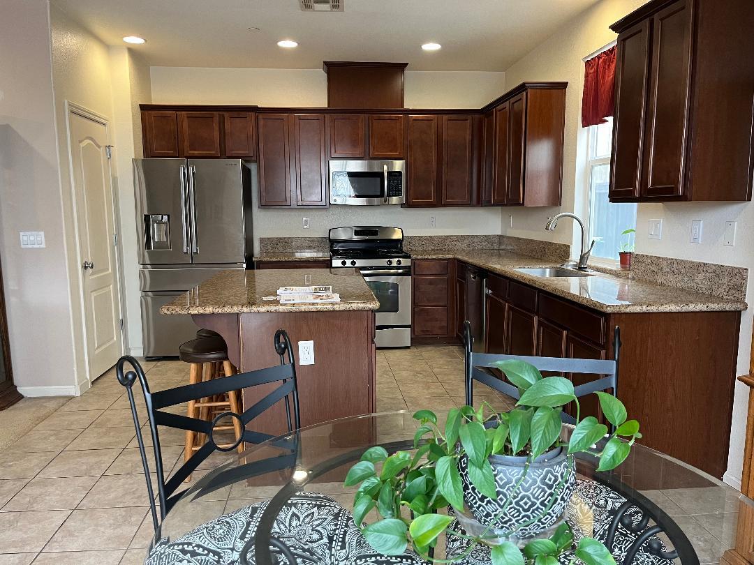 51 Sturla Way Gilroy, CA 95020 - Photo 2 of 27 a kitchen with kitchen island granite countertop stainless steel appliances a stove a sink a microwave a refrigerator and cabinets