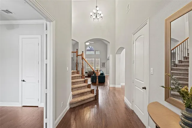 a view of a hallway with wooden floor staircase and a living room