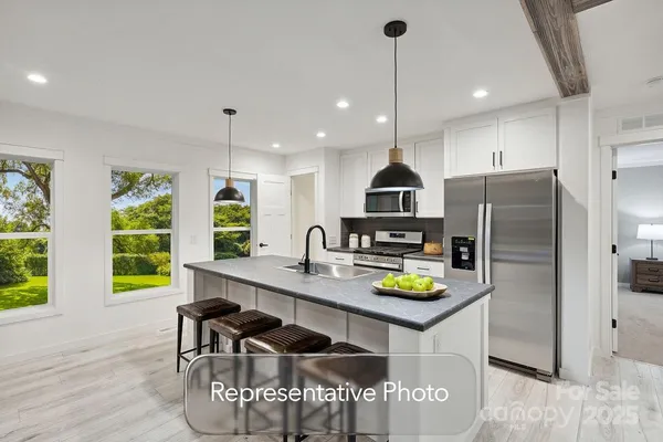 a kitchen with stainless steel appliances granite countertop a sink a stove a refrigerator a microwave a dining table and chairs with wooden floor