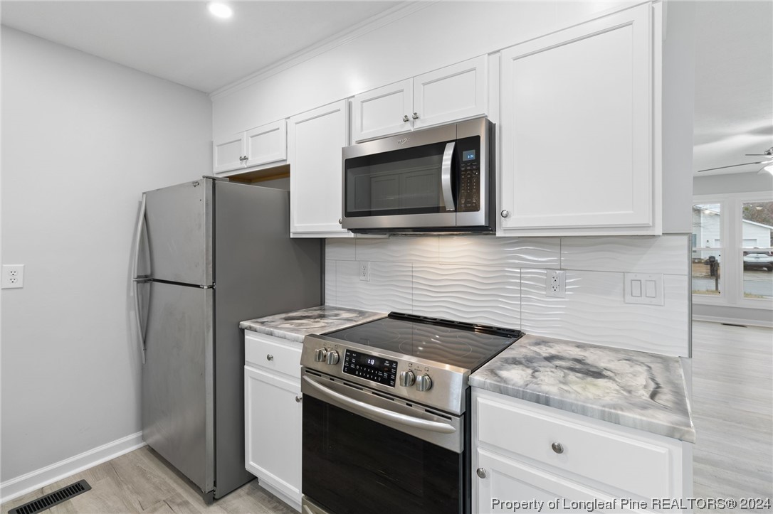 4108 Mill Bridge Road Hope Mills, NC 28348 - Photo 11 of 27 a kitchen with stainless steel appliances white cabinets and a stove