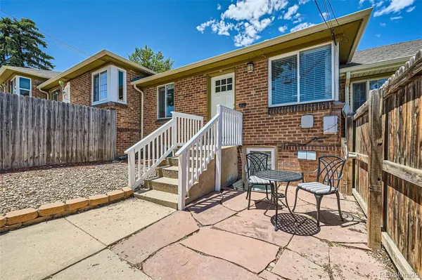 a view of a house with wooden stairs and a table and chairs