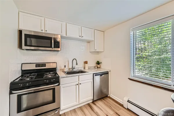 a kitchen with stainless steel appliances a stove a sink cabinets and a wooden floor