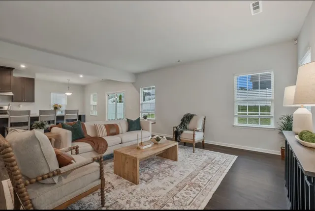 a living room with furniture couches and a dining table with wooden floor