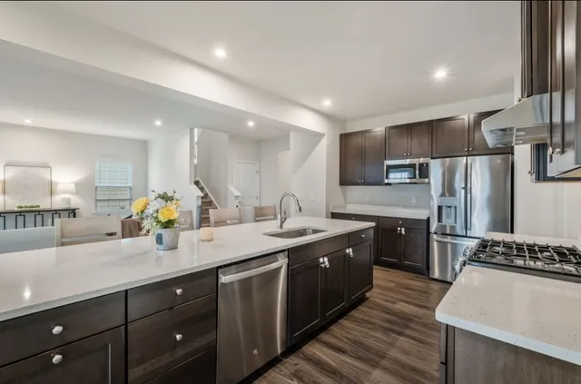 a large kitchen with stainless steel appliances granite countertop a sink a stove and a refrigerator