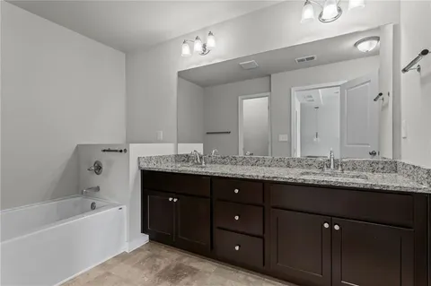 a bathroom with a granite countertop bathtub sink double and mirror