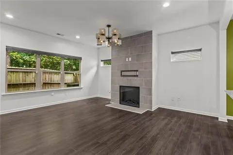 a view of an empty room with wooden floor fireplace and a window