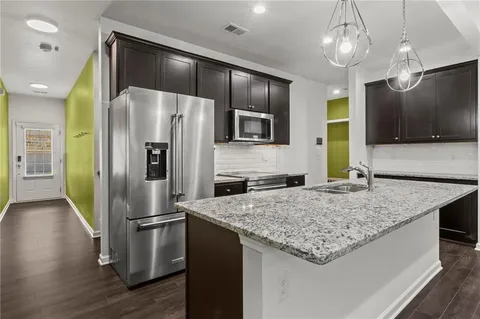 a kitchen with kitchen island a counter space a sink appliances and cabinets