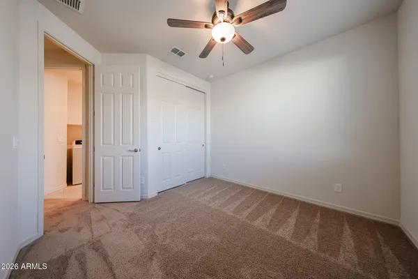 an empty room with closet and a chandelier fan