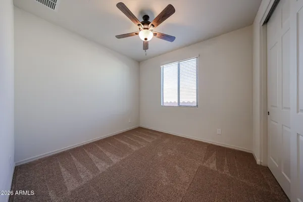 an empty room with windows and ceiling fan