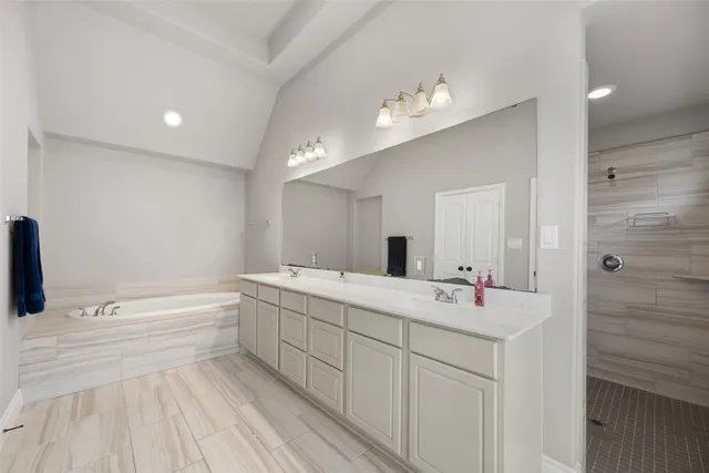a spacious bathroom with a double vanity sink a mirror and a bathtub