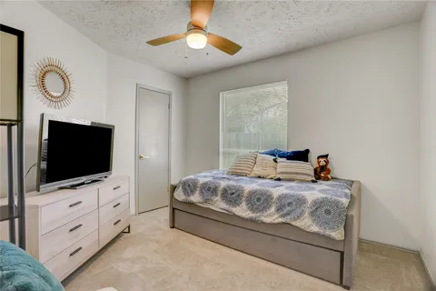 a bedroom with a bed and a flat tv screen on dresser