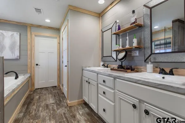 a spacious bathroom with a double vanity sink a mirror and a bathtub