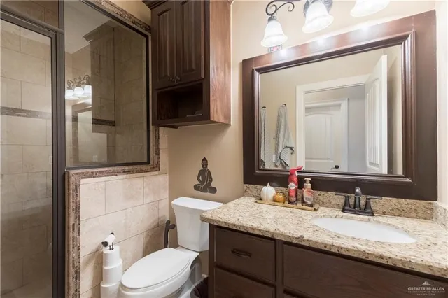 a bathroom with a granite countertop toilet sink and mirror