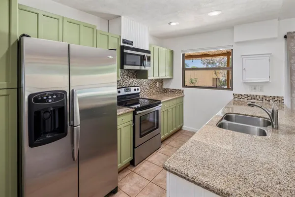 a kitchen with stainless steel appliances granite countertop a stove a refrigerator and a sink