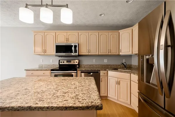 a kitchen with stainless steel appliances granite countertop a stove top oven a sink and a microwave