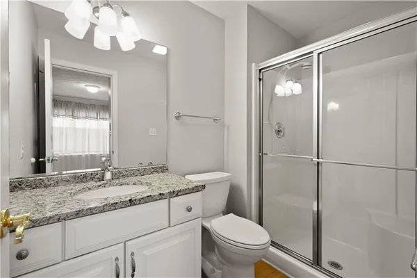 a bathroom with a granite countertop sink mirror vanity and toilet