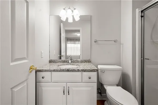 a bathroom with a granite countertop toilet sink and mirror