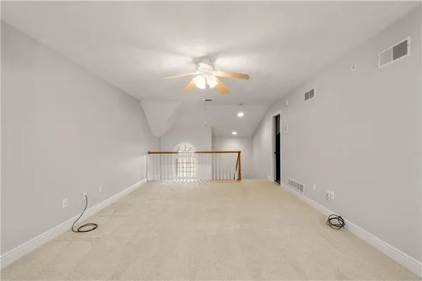 an empty room with chandelier fan and windows