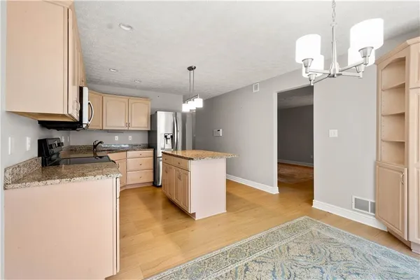 a kitchen with kitchen island granite countertop a sink a counter top space and stainless steel appliances