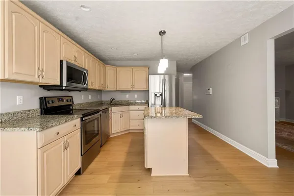 a kitchen with granite countertop a stove top oven a sink dishwasher and a refrigerator with wooden floor