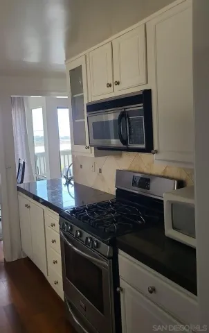 a kitchen with stainless steel appliances granite countertop white cabinets and black stove top oven