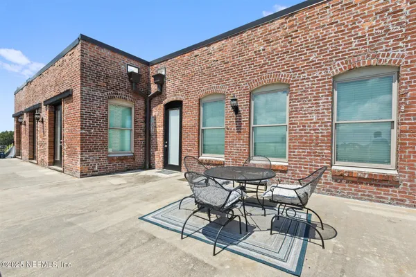 a patio with a table and chairs and potted plants