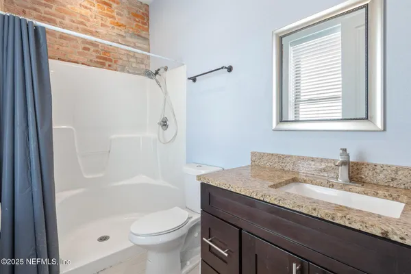 a bathroom with a granite countertop sink toilet and shower