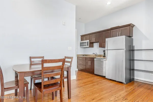 a kitchen with a table chairs refrigerator and microwave