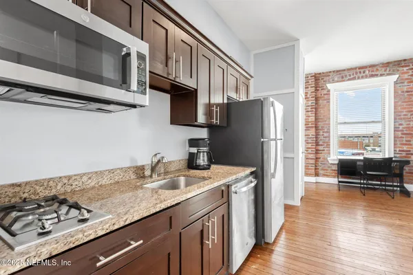 a kitchen with stainless steel appliances granite countertop a refrigerator a stove a sink and a microwave