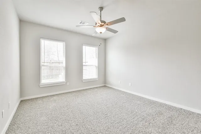 an empty room with a window and a ceiling fan