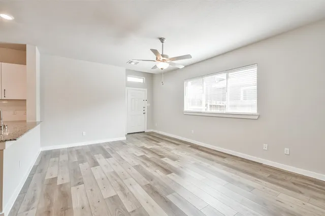 a view of an empty room with wooden floor and a window