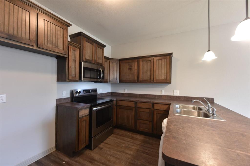 101 Capps Street, Unit A Rio Vista, TX 76093 - Photo 2 of 17 a kitchen with wooden cabinets a sink stove and microwave