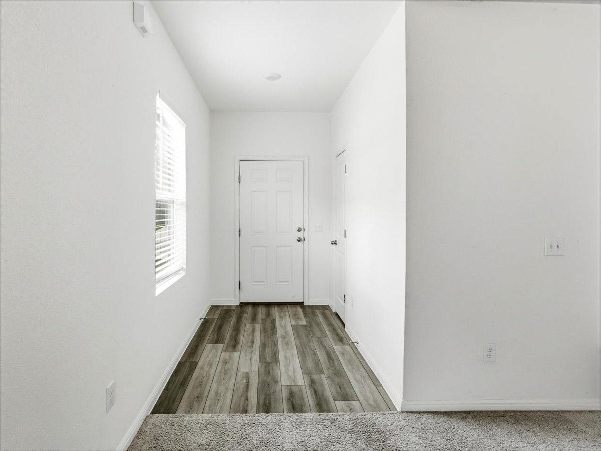 202 Peridot Pass Maxwell, TX 78656 - Photo 3 of 21 A welcoming entryway features wood-look flooring and a sun-filled window, leading into comfortable carpeted living space.
