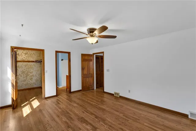 an empty room with wooden floor and a ceiling fan