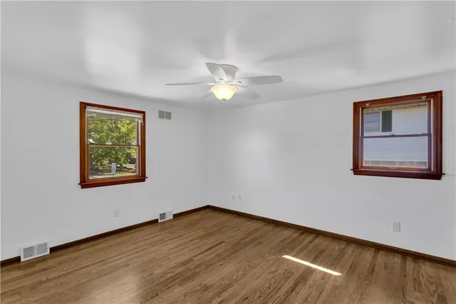 a view of an empty room with window and wooden floor