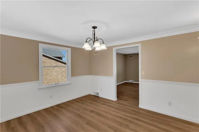 a view of an empty room with wooden floor and staircase