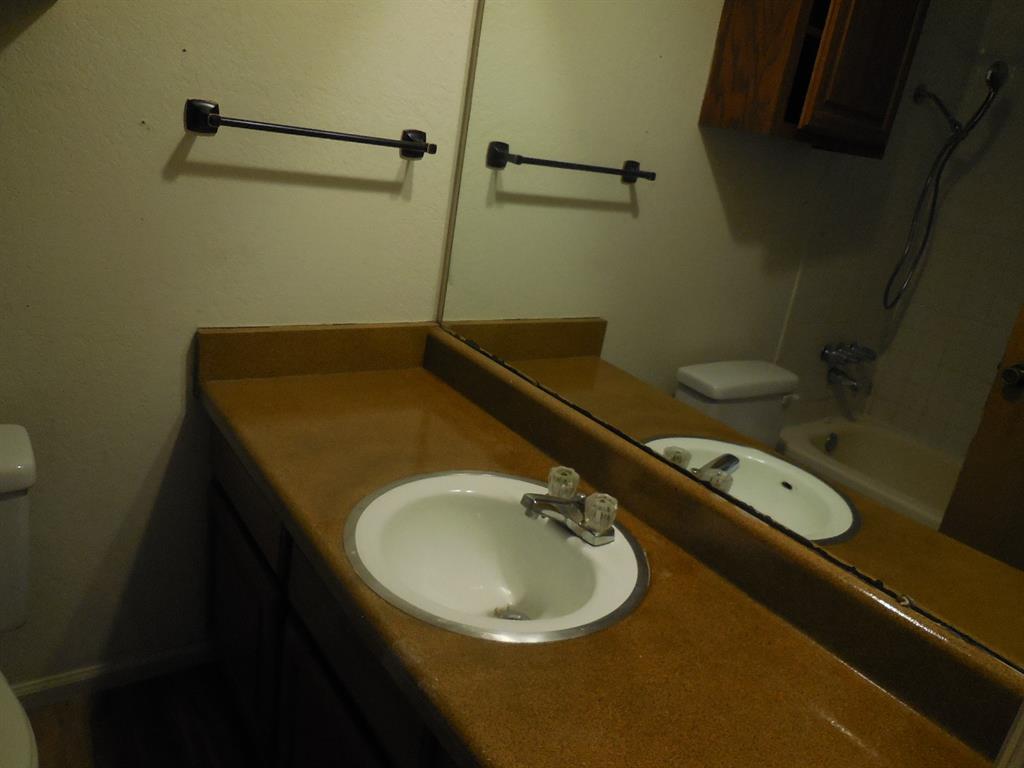 1220 Meadowbrook Street Ranger, TX 76470 - Photo 13 of 28 a bathroom with a granite countertop sink and a mirror