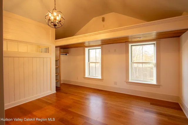 a view of a livingroom with a large window wooden floor and chandelier