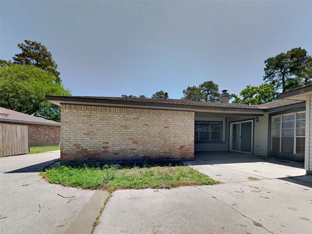 a view of a house with a small yard and a large parking space