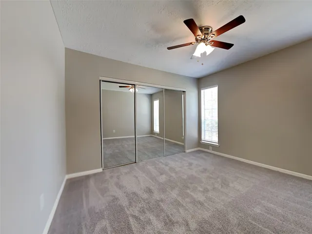 an empty room with closet and a ceiling fan