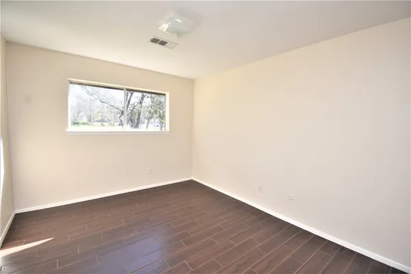 an empty room with wooden floor and window