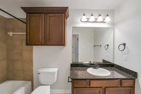 a bathroom with a granite countertop toilet sink and mirror