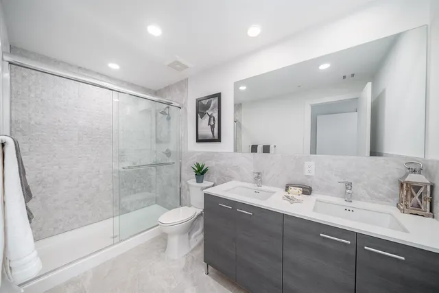 a bathroom with a double vanity sink toilet and shower