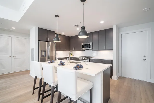 a kitchen with stainless steel appliances kitchen island granite countertop a kitchen island a stove a table and chairs