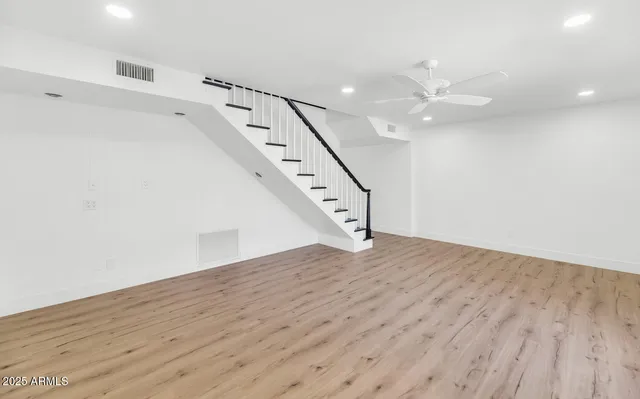 a view of an empty room with wooden floor and a ceiling fan