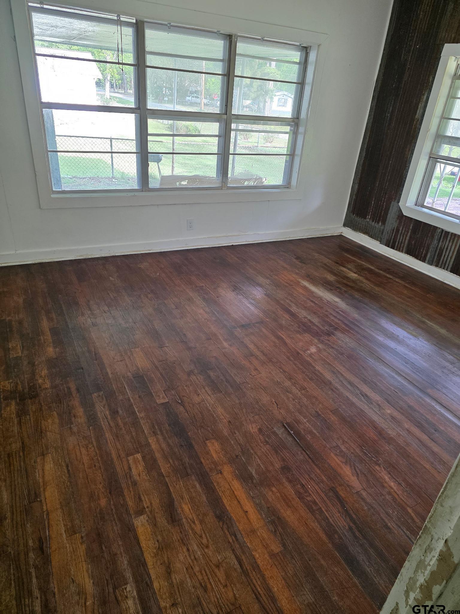 312 5th Street Southwest Bogata, TX 75417 - Photo 2 of 9 an empty room with wooden floor and windows