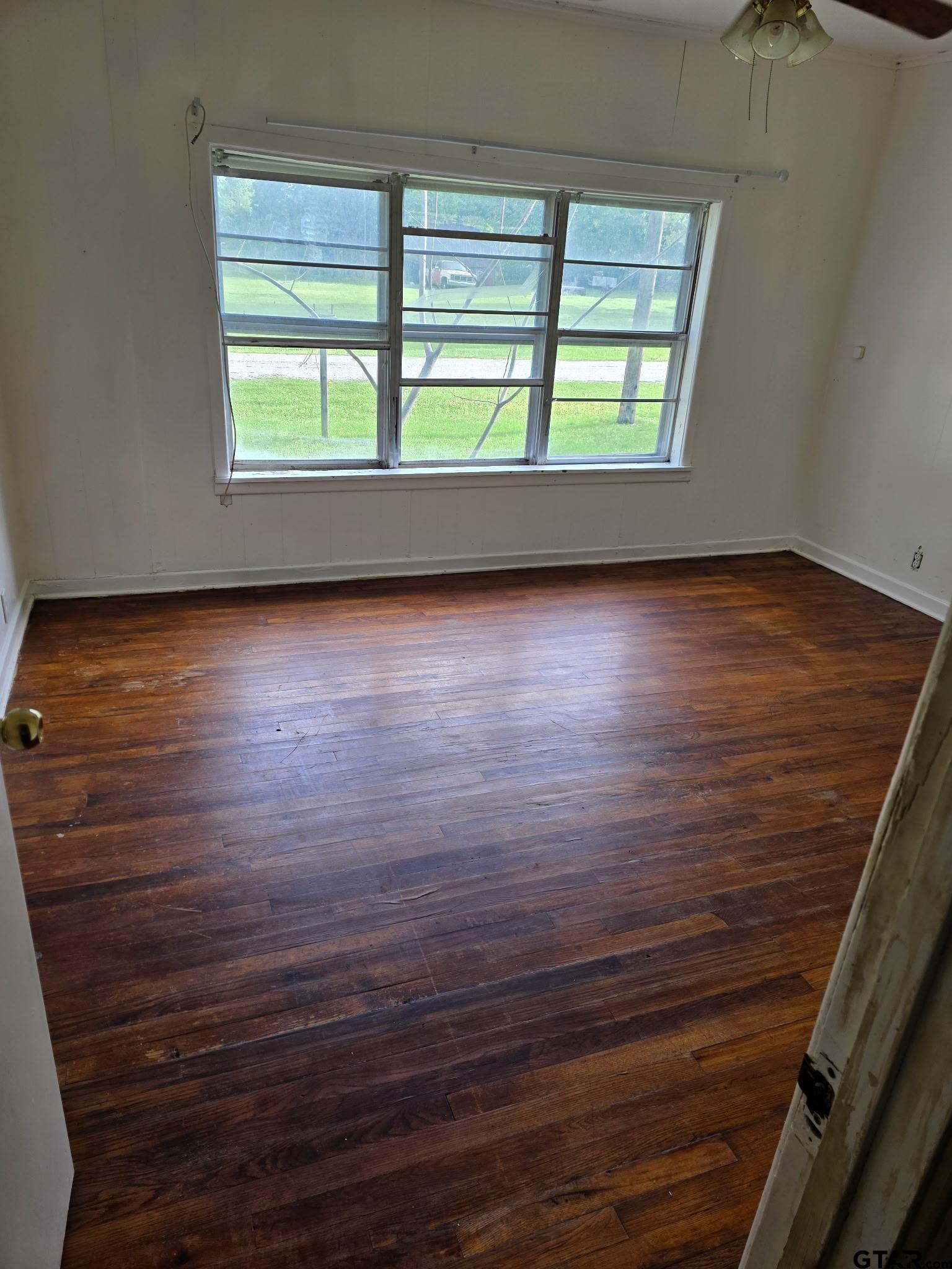 312 5th Street Southwest Bogata, TX 75417 - Photo 7 of 9 an empty room with wooden floor and windows
