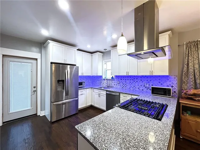 a kitchen with stainless steel appliances kitchen island granite countertop a stove refrigerator and cabinets