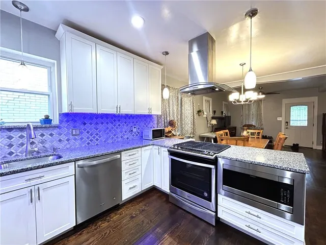 a kitchen with kitchen island granite countertop stainless steel appliances and wooden cabinets