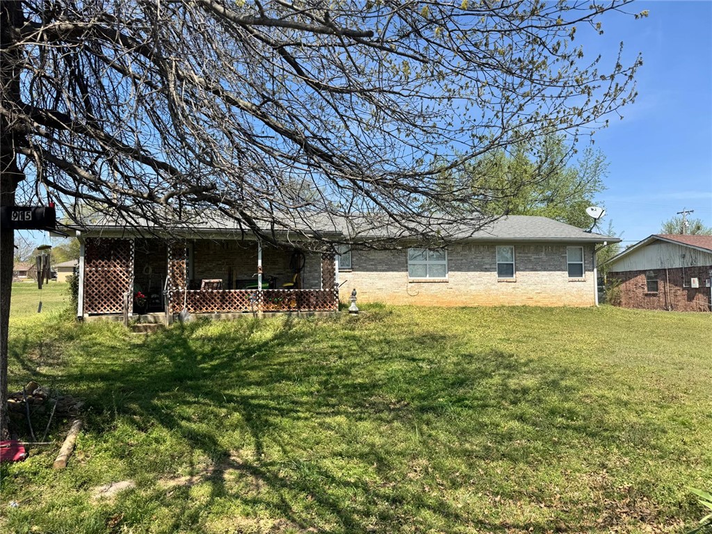 Rear view of house with brick siding and a yard